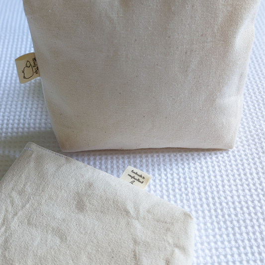 Close up of Wooly Tops cotton canvas snap bags in large and small with black brass snaps.